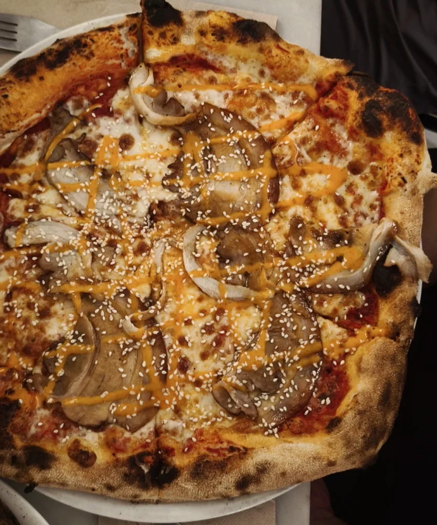 Pizza Japonesa de Agarre Pizzería con chashu, berza fermentada, salsa japonesa y sésamo