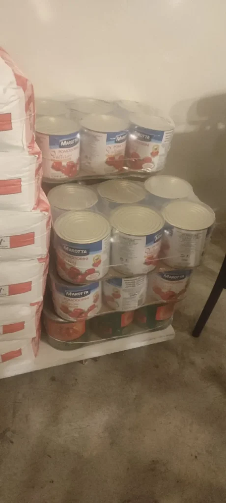 Sacos de harina y latas de tomate apilados al fondo de Gagootz