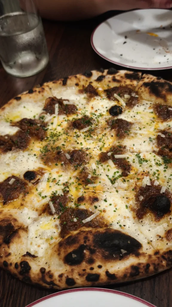 Pizza blanca con trozos de carne y borde tostado en Gagootz