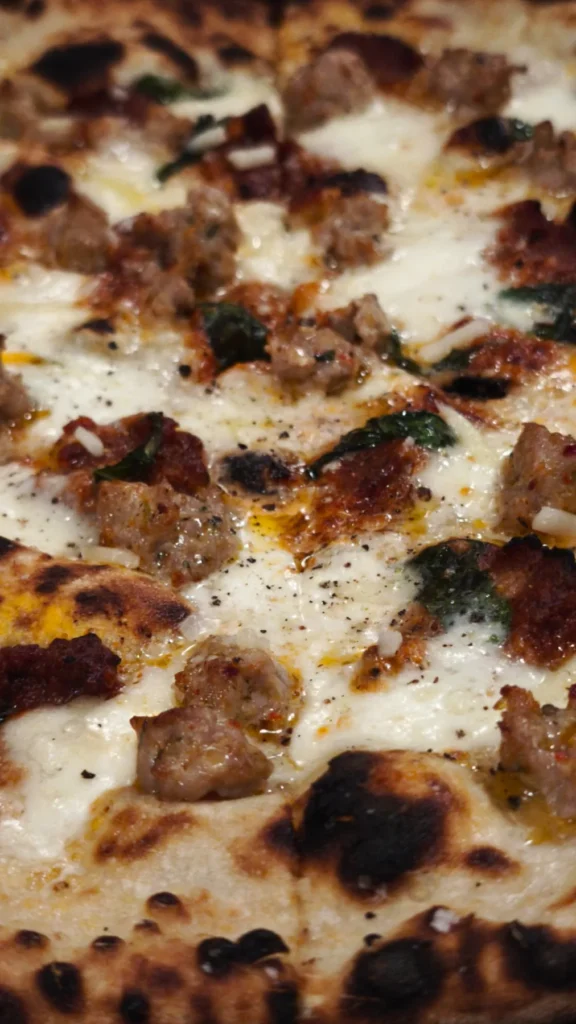 Primer plano de una pizza blanca con carne y hierbas en Gagootz