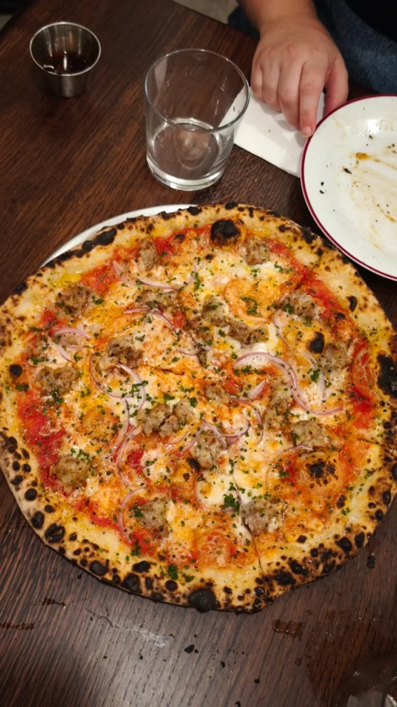 Pizza con tomate, carne y cebolla morada sobre la mesa de Gagootz
