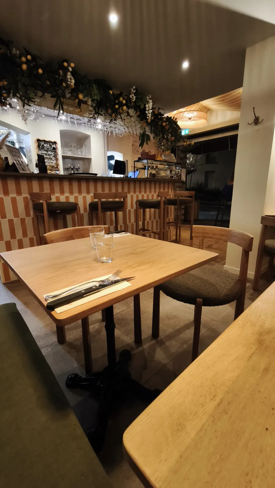 Interior de Loujo Biarritz con mesas de madera, banco corrido y luz cálida