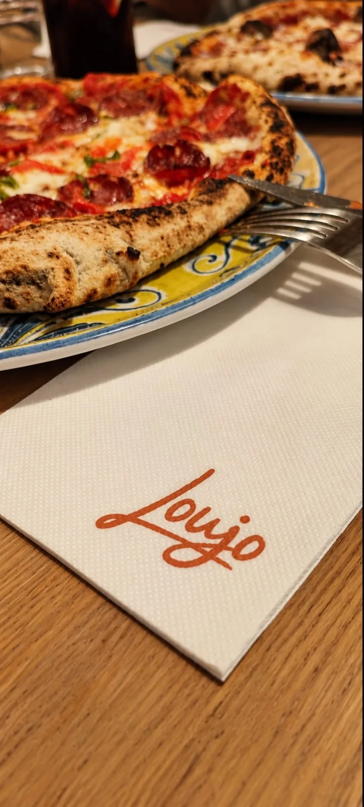 Detalle de una pizza servida en Loujo Biarritz junto a una servilleta